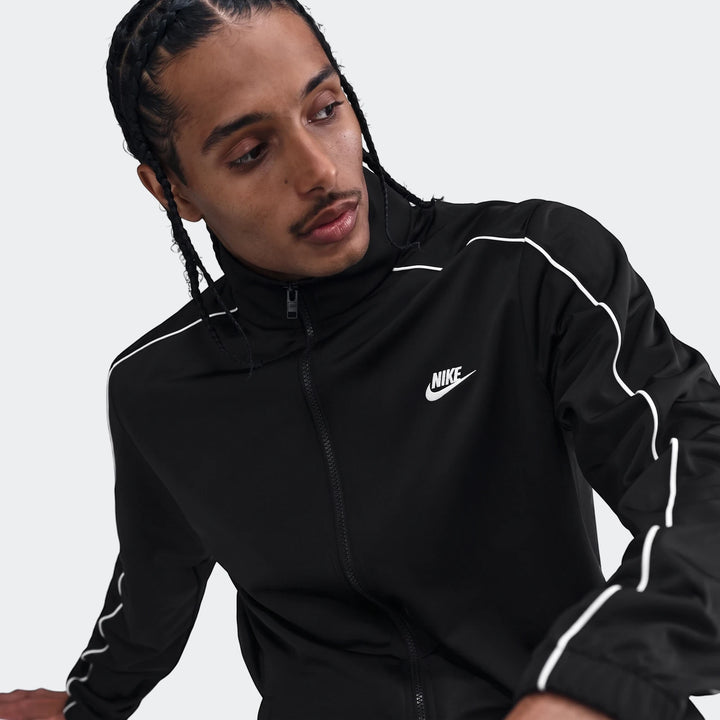 Man wearing a black Nike Sportswear Club poly-knit tracksuit jacket with white piping, featuring the Nike logo.