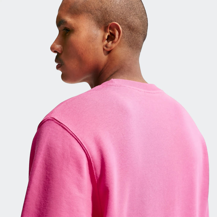 Male model wearing a Nike Sportswear Club pink French Terry crew-neck sweatshirt, viewed from the back-right shoulder.
