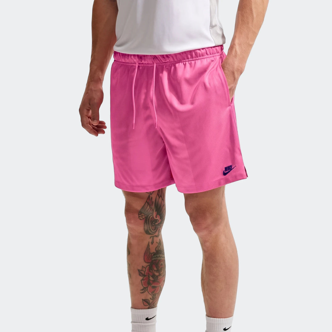 Pink Nike Sportswear Club Flow Shorts for men, shown worn by a model from the waist down in a studio shot.