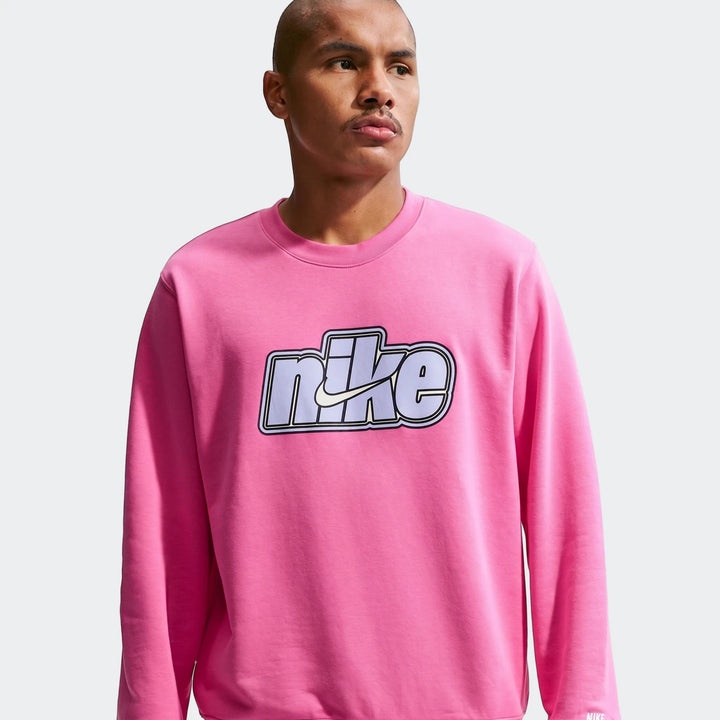A man wears a pink Nike Sportswear Club Red French Terry crew-neck sweatshirt, featuring a prominent logo on the chest.