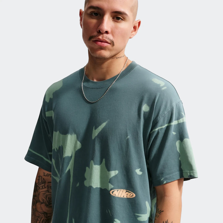 Male model wearing a Nike Sportswear green tie-dye t-shirt with a silver chain, captured from the chest up.
