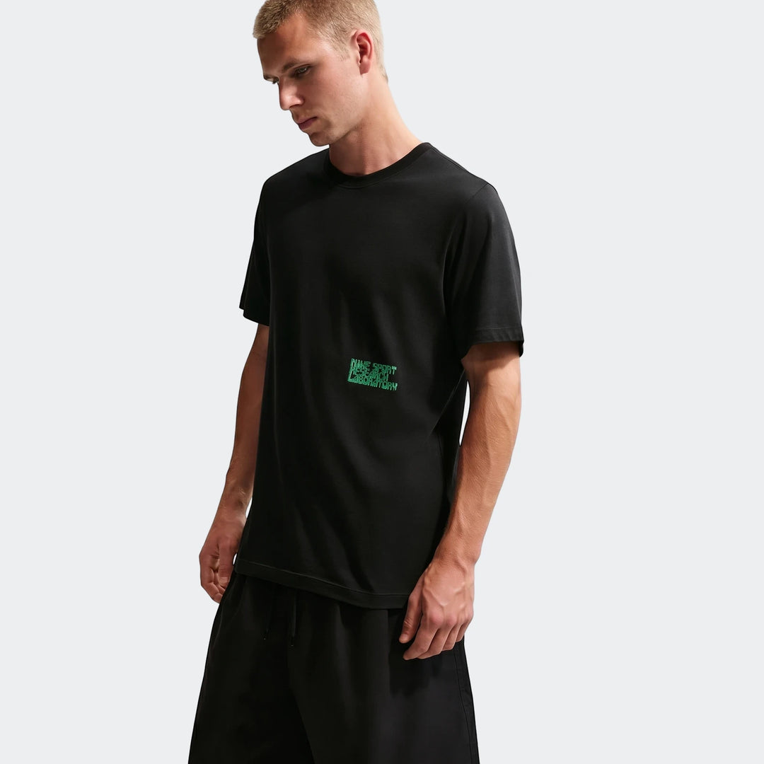 Men's Nike Sportswear black short-sleeve t-shirt with green logo worn by a male model, shown waist-up.