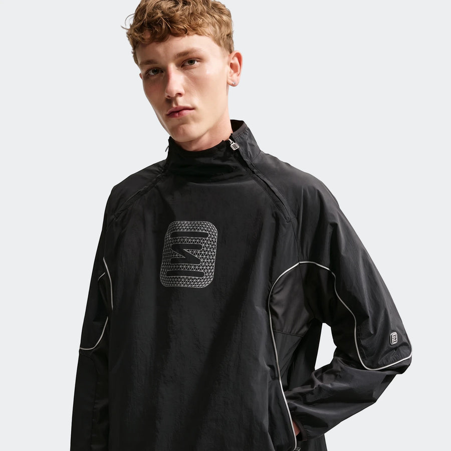 Male model wearing a black Nike Sportswear men's woven jacket with white piping and a textured chest logo.