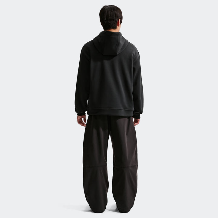 Men's black Nike Sportswear fleece pullover hoodie and black baggy pants, captured from the back view, showcasing its