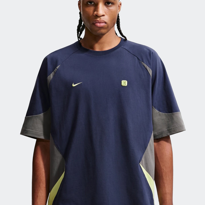 Nike Sportswear Men's Short-Sleeve Top in navy blue, grey, and neon yellow, shown on a model from the front.