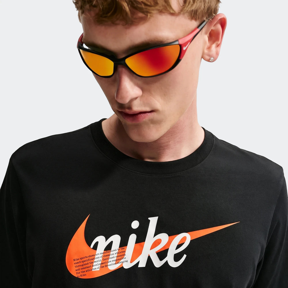 Close-up of a man wearing a black Nike Sportswear t-shirt with an orange logo, paired with red and black sports sunglasses.