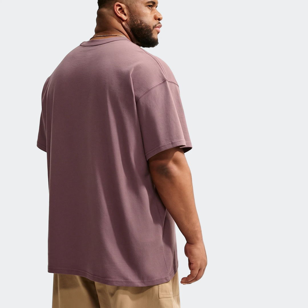 Mauve Nike Sportswear Premium Essentials men's oversized short-sleeve t-shirt worn by a man, viewed from the back.