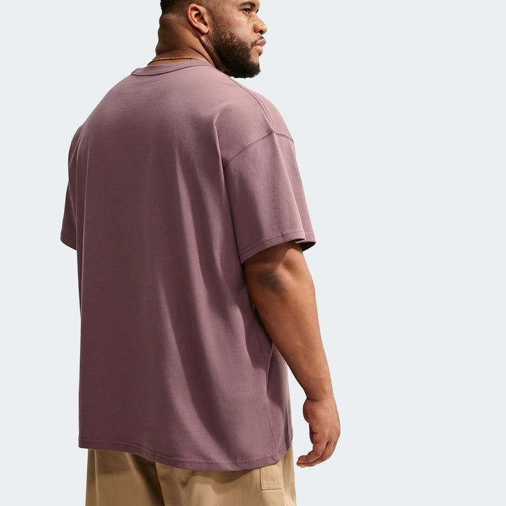 Mauve Nike Sportswear Premium Essentials men's oversized short-sleeve t-shirt worn by a man, viewed from the back.