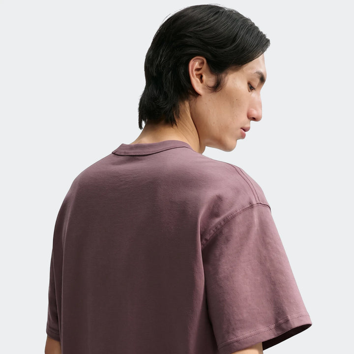 Man wearing a plum Nike Sportswear Premium Essentials men's short-sleeve t-shirt, viewed from the back and side.