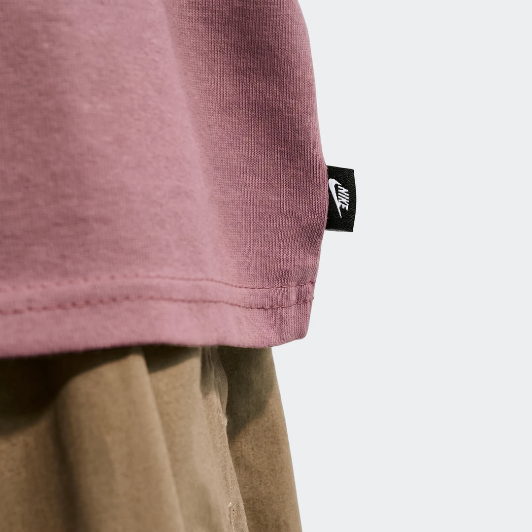 Close-up of a Nike Sportswear Premium Essentials men's t-shirt in pinkish-purple, showcasing its ribbed fabric and a black