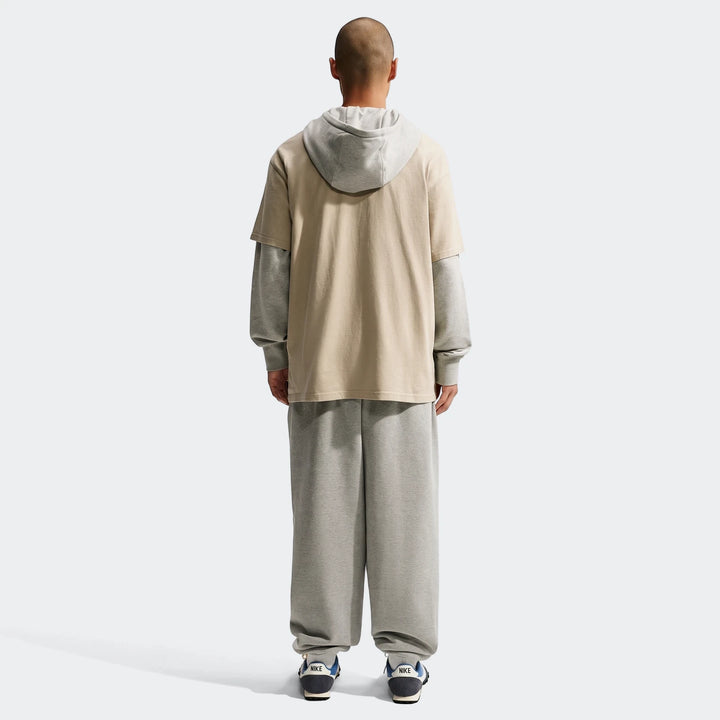Nike Sportswear Premium Essentials T-Shirt layered over a gray long-sleeve tee, worn with gray sweatpants by a male model