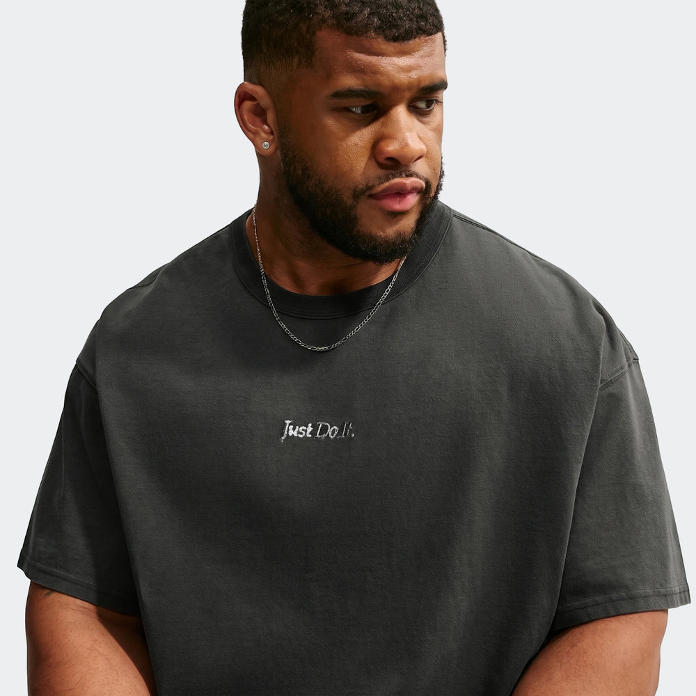Male model wearing a black Nike Sportswear Premium Essentials T-Shirt with 'Just Do It.' embroidery and a silver chain