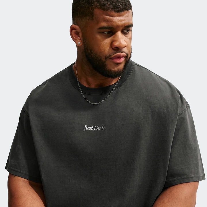 Male model wearing a black Nike Sportswear Premium Essentials T-Shirt with 'Just Do It.' embroidery and a silver chain