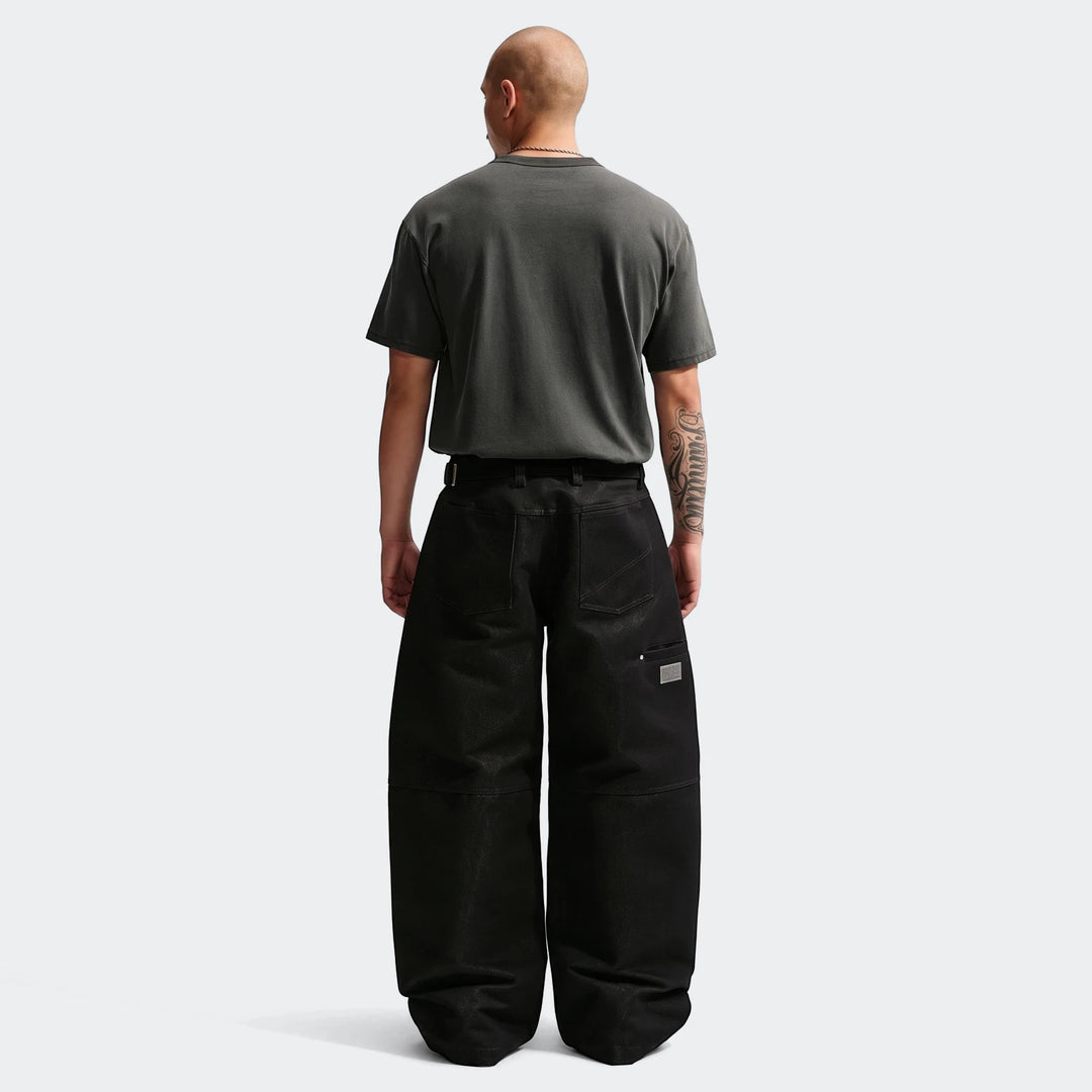 Bald man wearing a charcoal Nike Sportswear Premium Essentials T-Shirt and black wide-leg pants, shown from the back.