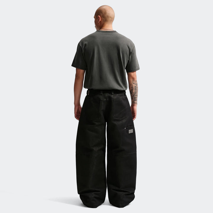 Bald man wearing a charcoal Nike Sportswear Premium Essentials T-Shirt and black wide-leg pants, shown from the back.