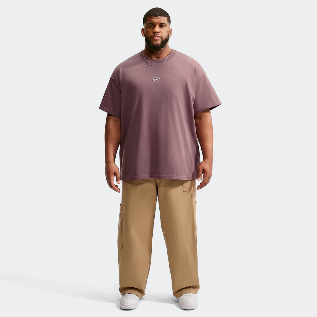 A man models a plum Nike Sportswear Premium Essentials T-shirt and khaki cargo pants, paired with white sneakers, standing