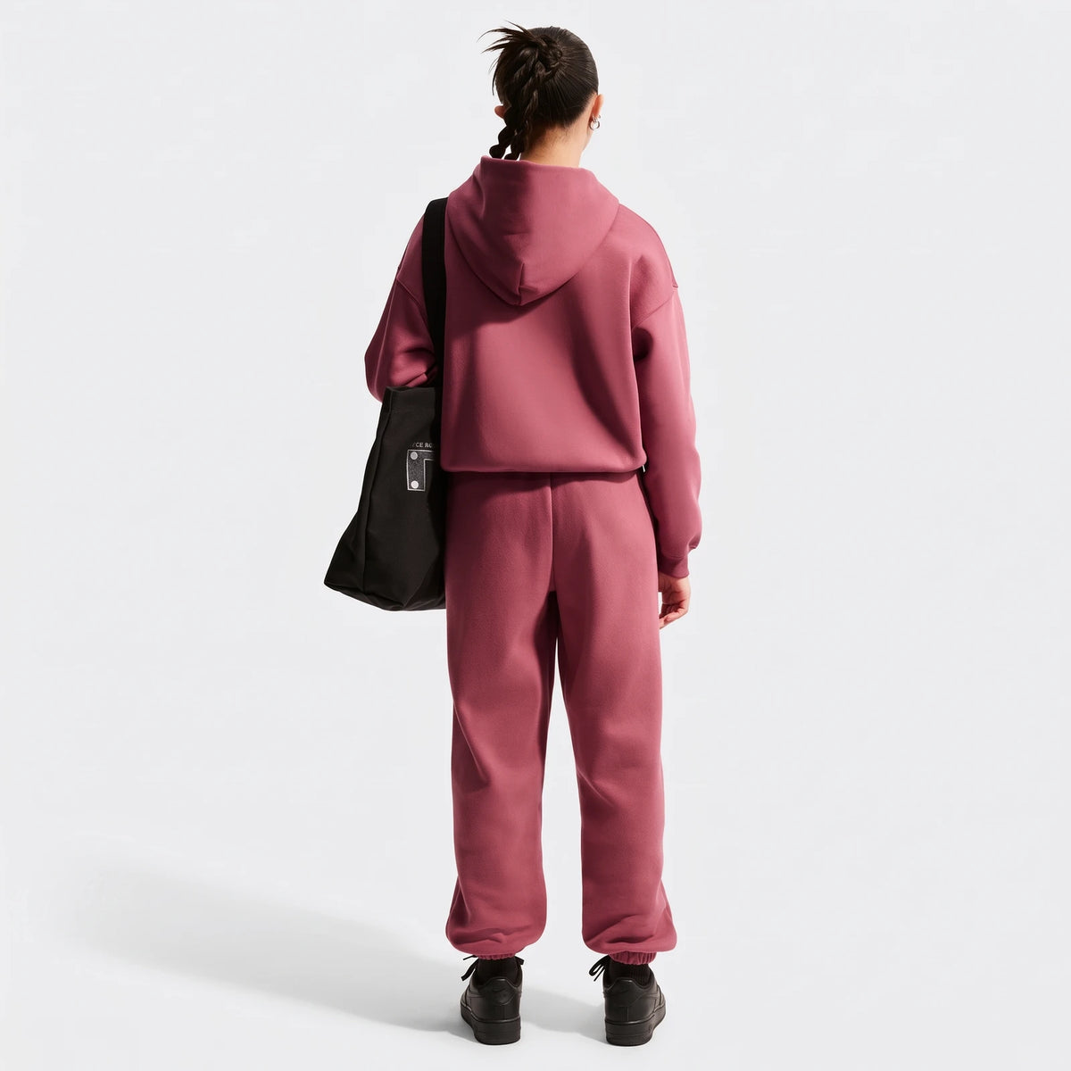 Rear view of a young person wearing a dusty rose Nike Sportswear Studio Fleece oversized full-zip hoodie and matching