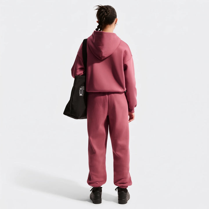 Rear view of a young person wearing a dusty rose Nike Sportswear Studio Fleece oversized full-zip hoodie and matching