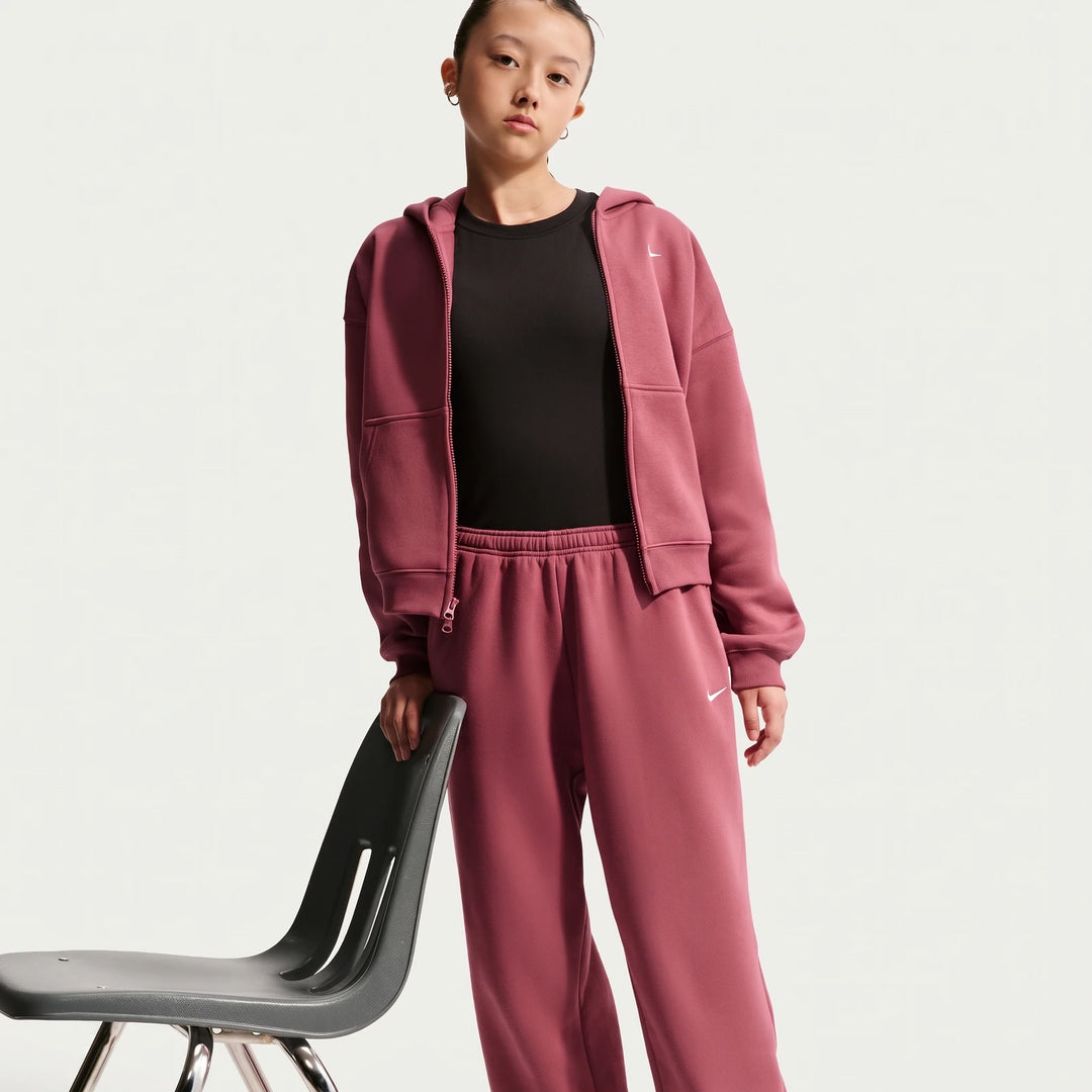 Nike Sportswear Studio Fleece Girls' Loose Pants in dark pink, worn by a young woman with a matching hoodie, standing next
