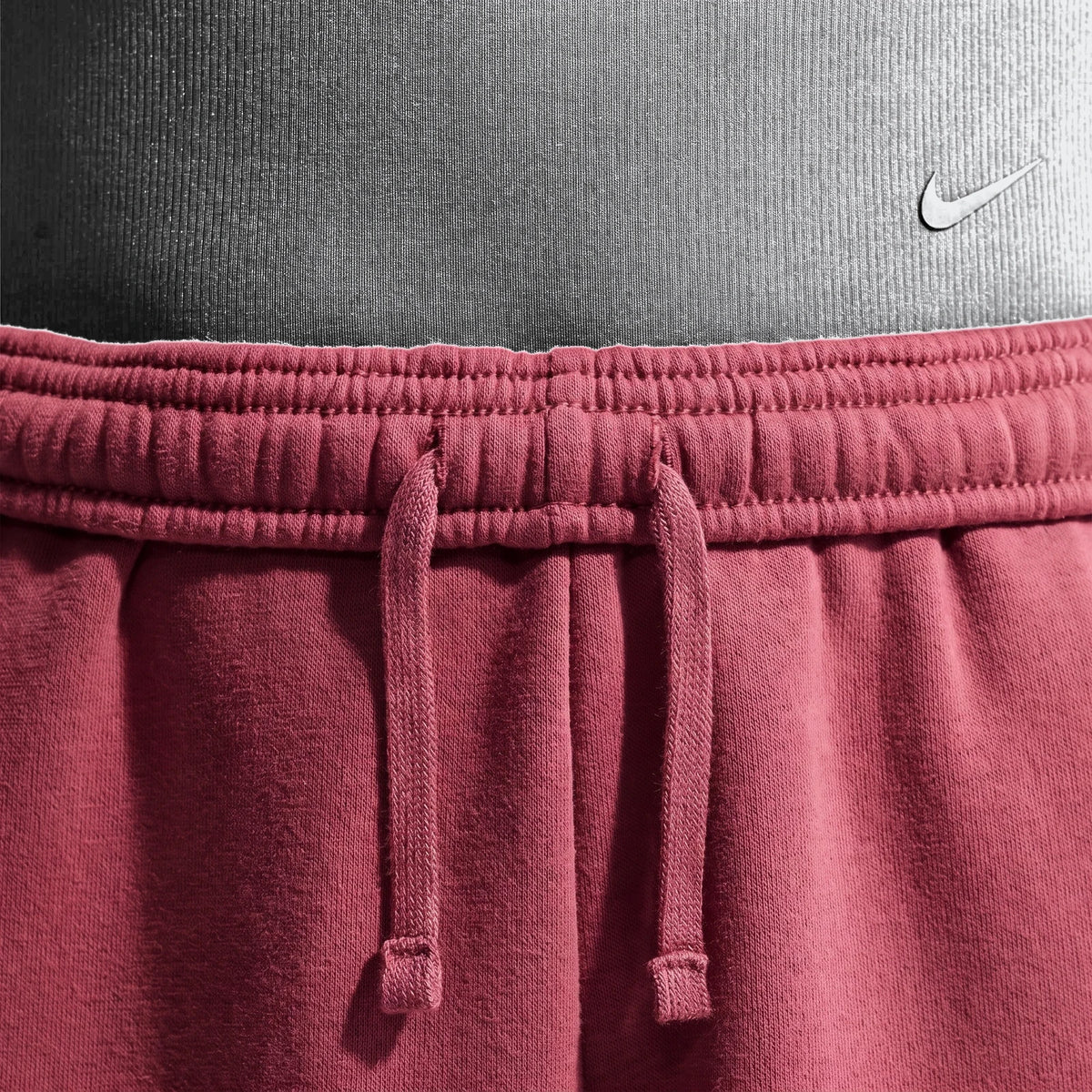 Close-up of Nike Sportswear Studio Fleece Girls' Loose Pants in maroon, showcasing the elastic waistband, drawstring, and