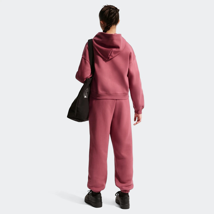 Rear view of a girl wearing Nike Sportswear Studio Fleece Loose Pants in pink/mauve, paired with a matching hoodie and black