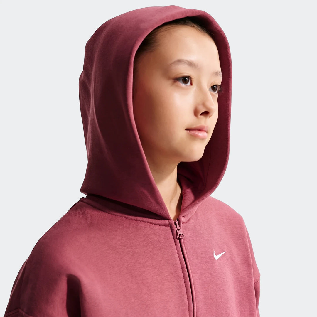 Young girl modeling an oversized Nike Sportswear Studio Fleece Full-Zip Hoodie in maroon on a plain background.