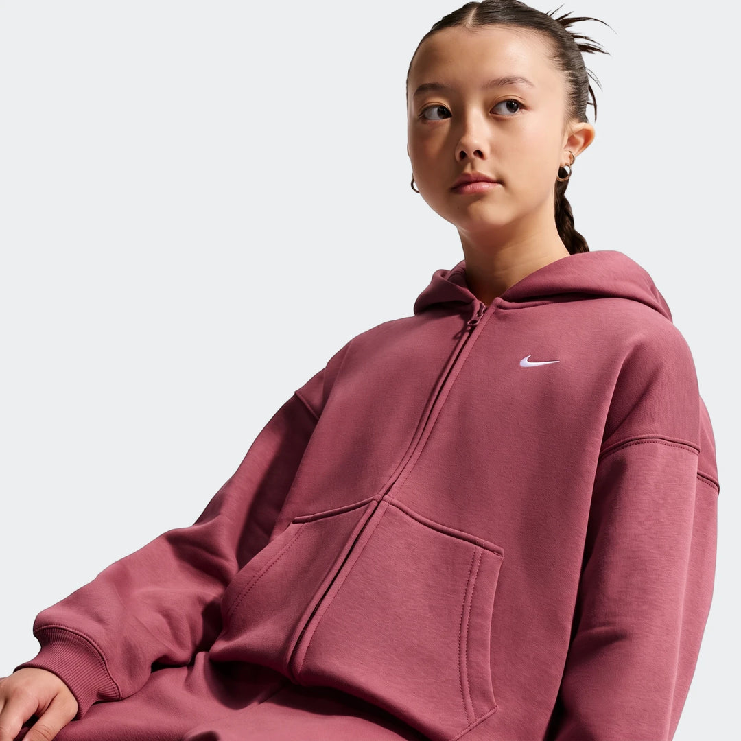 A young girl wears a Nike Sportswear Studio Fleece Oversized Full-Zip Hoodie in a dark pink color, viewed from the waist up.
