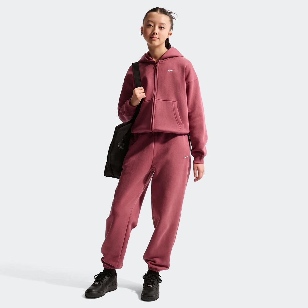 Young girl wearing a mauve Nike Sportswear Studio Fleece oversized full-zip hoodie, matching sweatpants, and black sneakers,