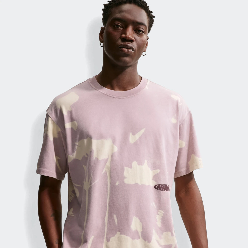 Front view of a male model wearing a Nike Sportswear tie-dye t-shirt in light purple and cream with Nike swoosh and logo.