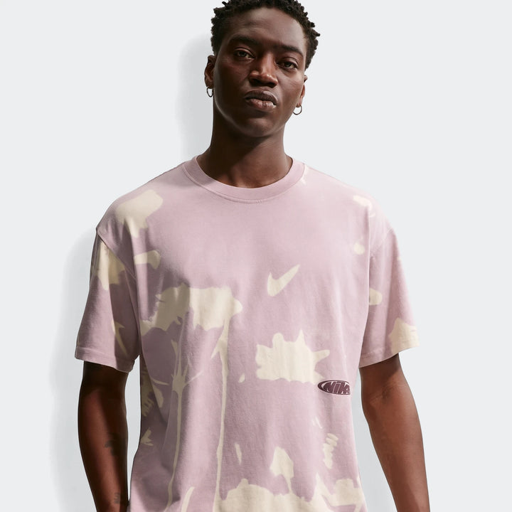 Front view of a male model wearing a Nike Sportswear tie-dye t-shirt in light purple and cream with Nike swoosh and logo.