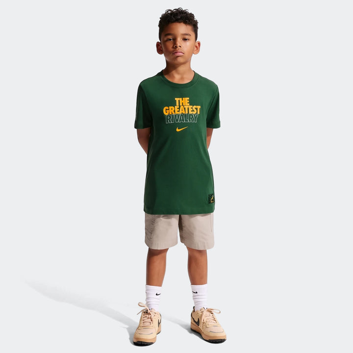 Young boy wearing a green Nike Springboks Rugby’s Greatest Rivalry Tour kids t-shirt, beige shorts, and sneakers.