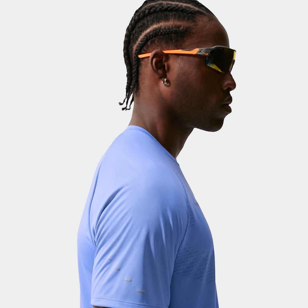 Profile view of a man wearing a Nike Stride Blue Men's Dri-Fit Adv Short-Sleeve Running Top and orange-accented sunglasses.