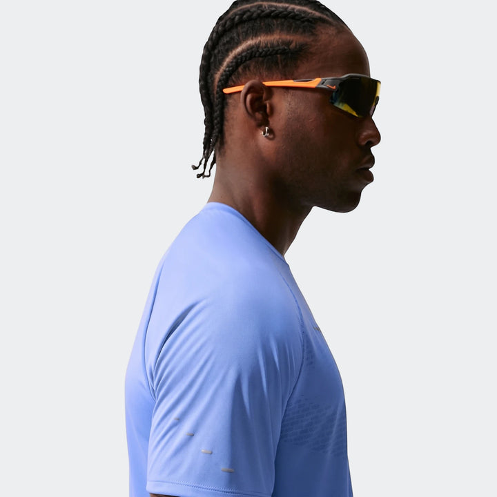 Profile view of a man wearing a Nike Stride Blue Men's Dri-Fit Adv Short-Sleeve Running Top and orange-accented sunglasses.