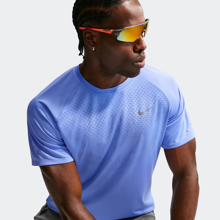 Close-up of a man wearing a blue Nike Stride Dri-Fit ADV short-sleeve running top with reflective details and sunglasses.