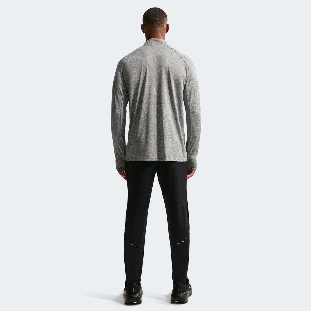 Rear view of a man wearing a grey Nike Stride Dri-Fit 1/4-Zip running top and black running pants.