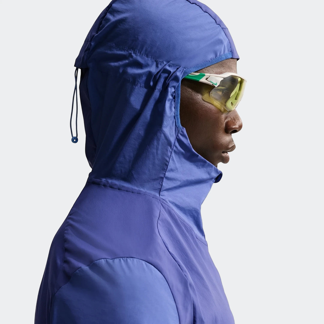 Nike Stride Plus Blue Men's Repel Running Jacket worn by a model in profile, featuring a hood and sports sunglasses.