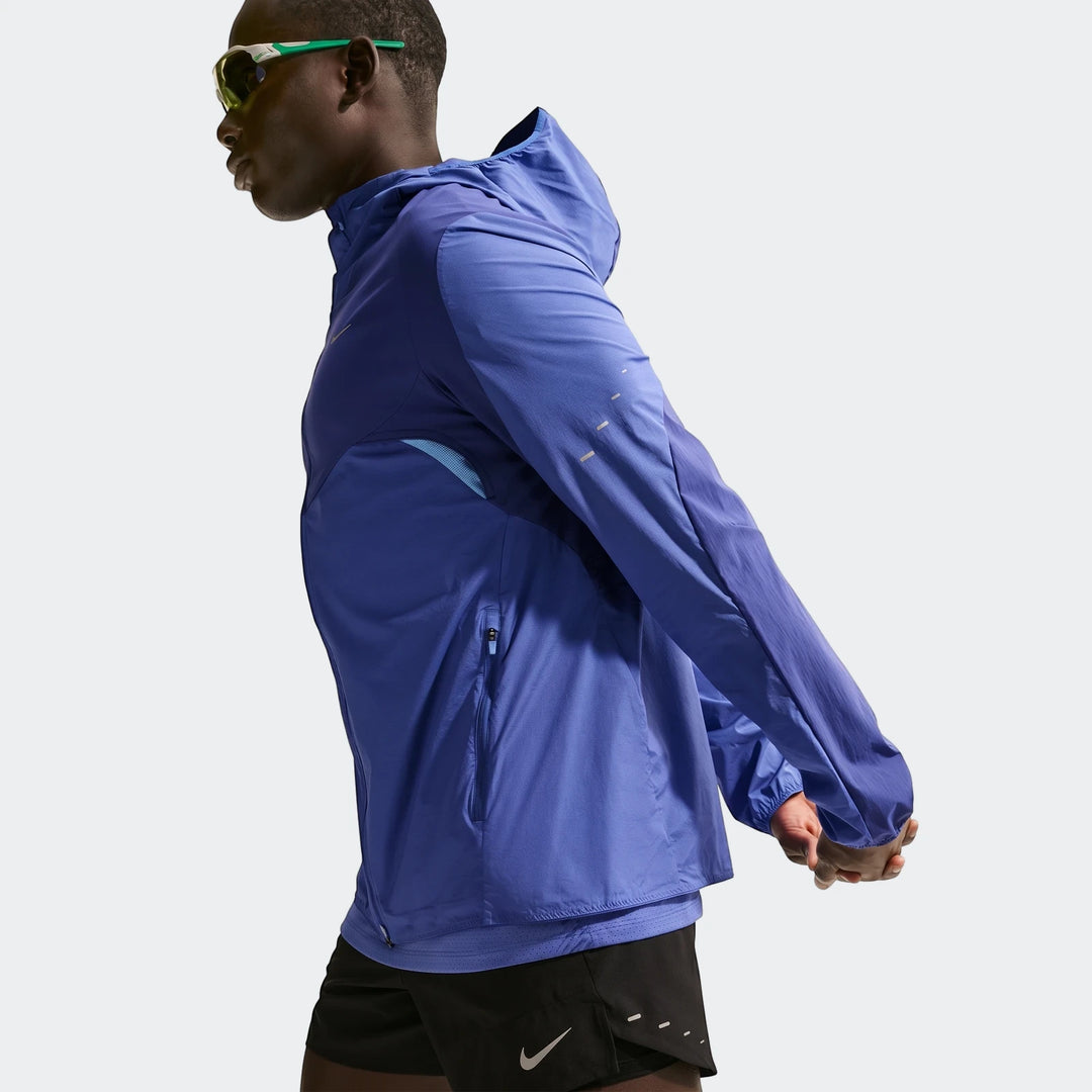 Nike Stride Plus Blue Men's Repel Running Jacket on a model, shown from mid-torso up, stretching.