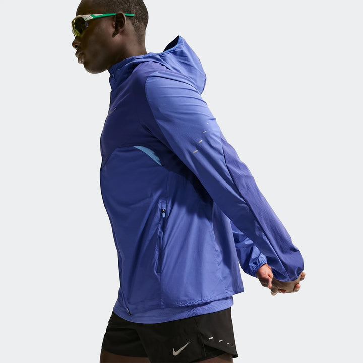 Nike Stride Plus Blue Men's Repel Running Jacket on a model, shown from mid-torso up, stretching.