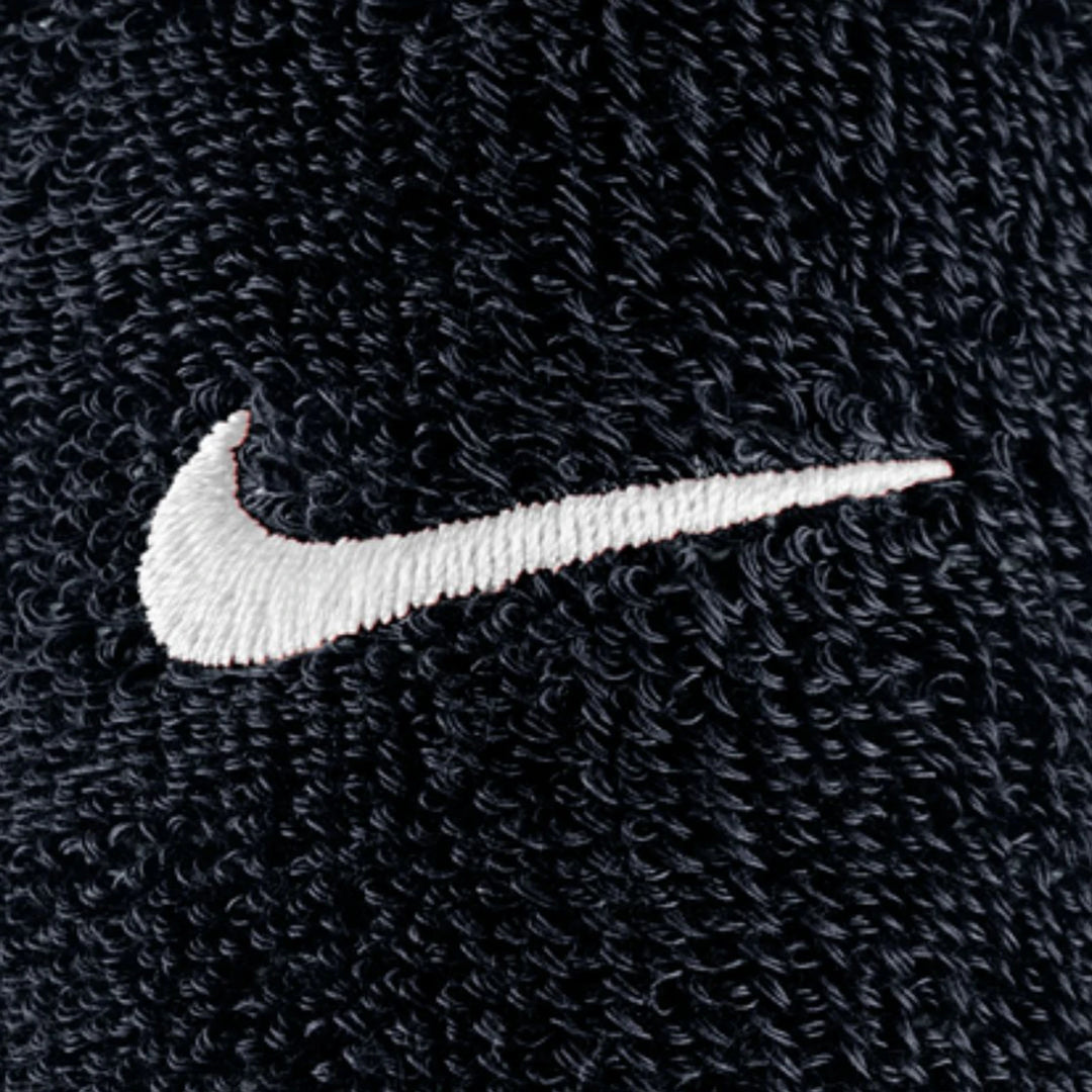 Close-up of a white Nike Swoosh logo embroidered on the black textured fabric of Swoosh Classic D Black Wristbands.