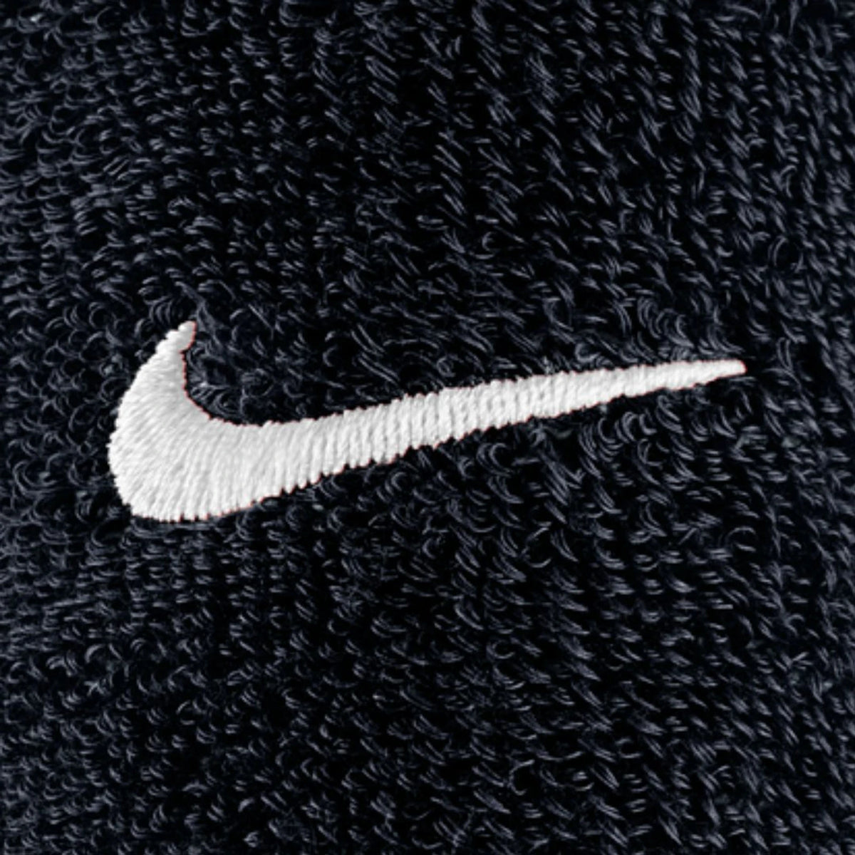 Close-up of a white Nike Swoosh logo embroidered on the black textured fabric of Swoosh Classic D Black Wristbands.