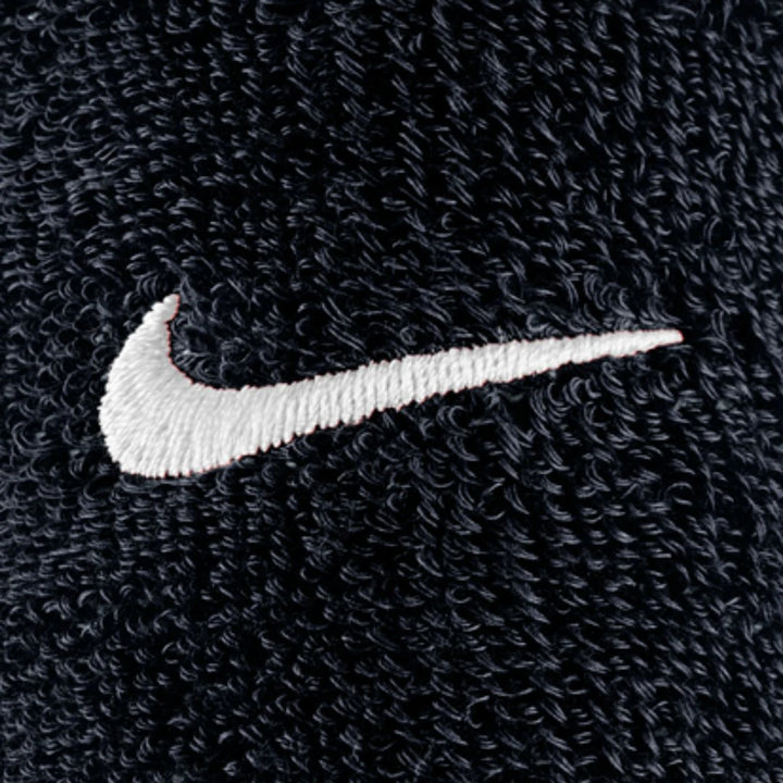 Close-up of a white Nike Swoosh logo embroidered on the black textured fabric of Swoosh Classic D Black Wristbands.