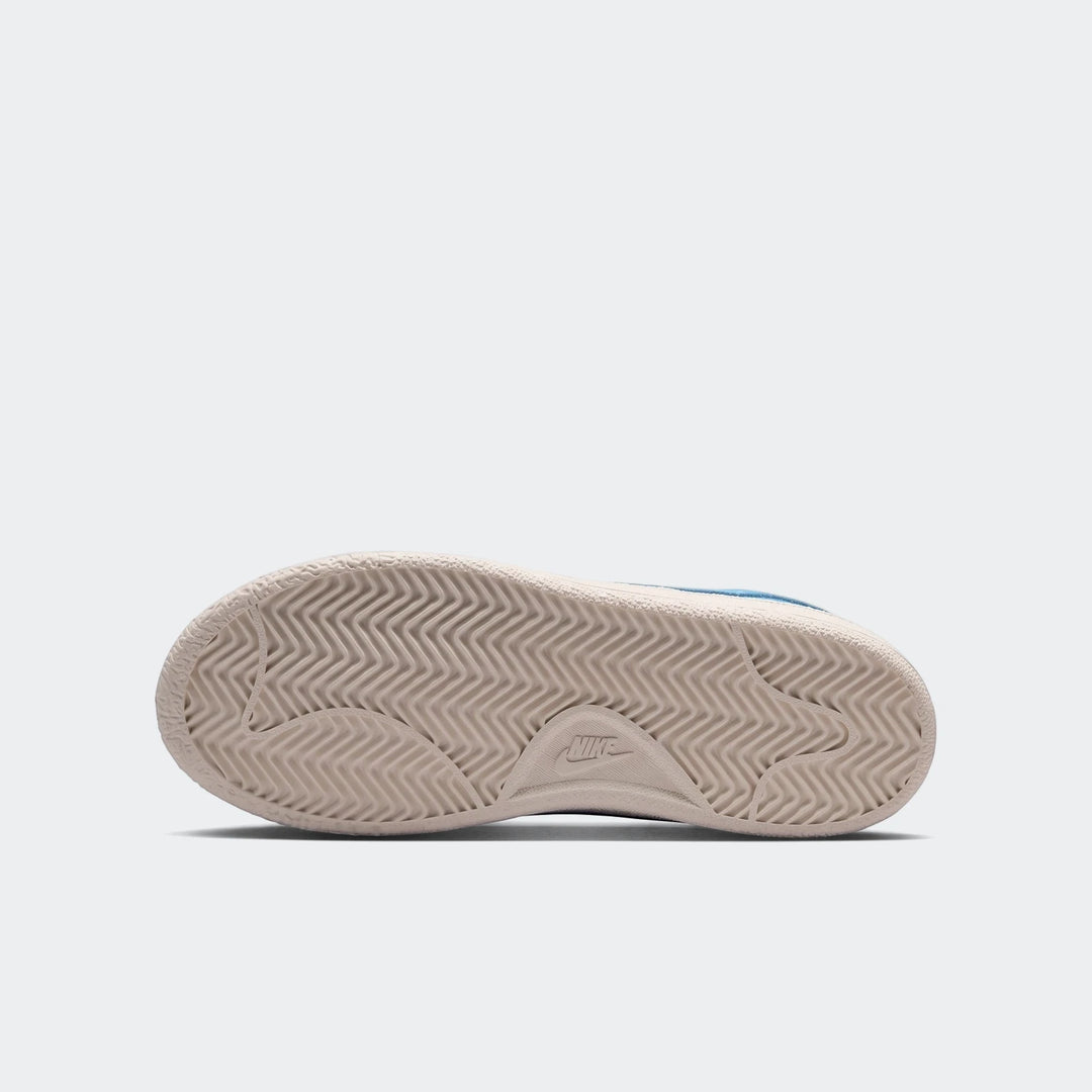 Bottom sole of a Nike Tennis Classic Big Kids' shoe, showing a beige textured outsole with a wavy pattern and Nike logo.