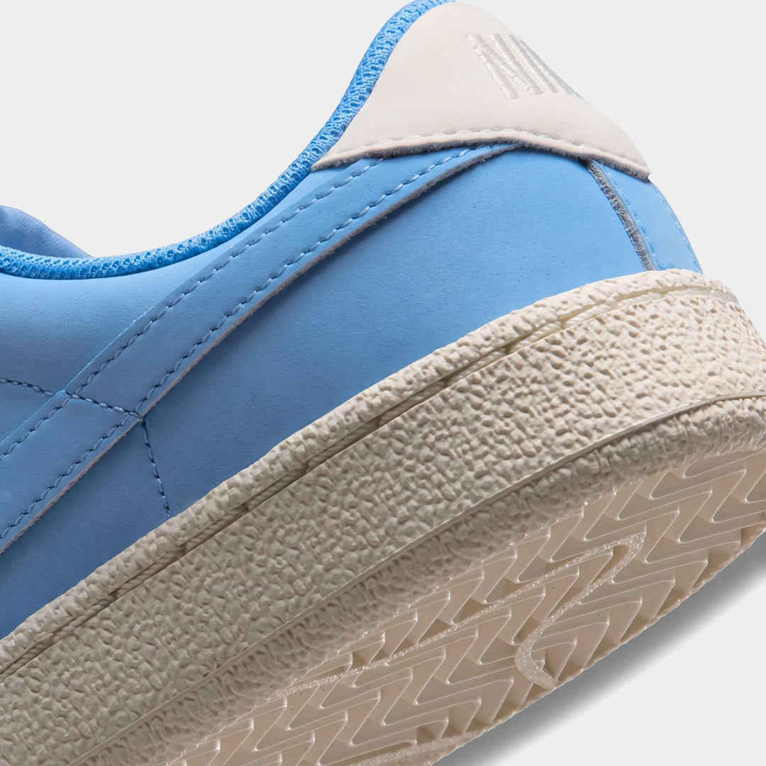 Close-up of a light blue Nike Tennis Classic Big Kids' shoe, showing the textured cream sole and heel counter with branding.