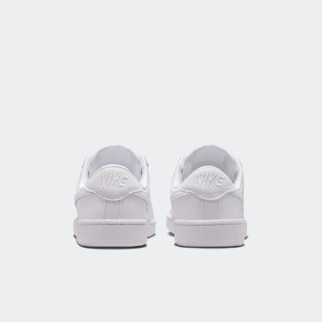 Rear view of two white Nike Tennis Classic Big Kids' shoes, showcasing the clean leather uppers and the embossed Nike logo