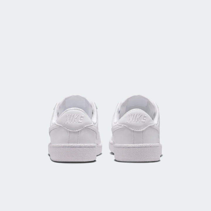 Rear view of two white Nike Tennis Classic Big Kids' shoes, showcasing the clean leather uppers and the embossed Nike logo