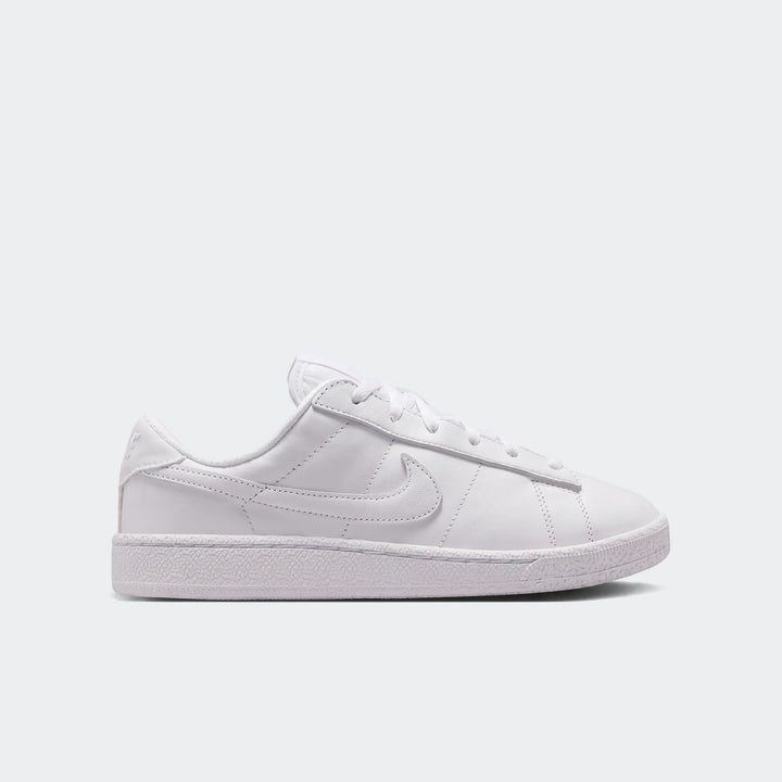 White Nike Tennis Classic Big Kids' shoes, shown in a side profile, featuring a smooth leather upper and classic swoosh