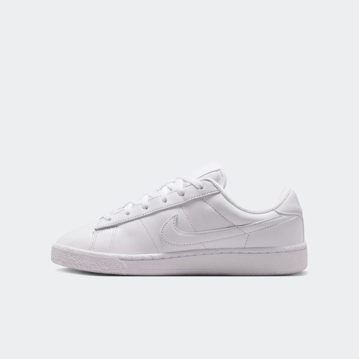 White Nike Tennis Classic Big Kids' Shoes, side view, made of leather-like material with laces and a rubber sole.