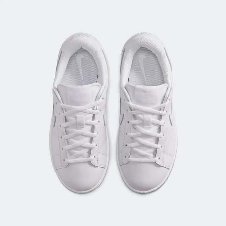 Top-down view of two white Nike Tennis Classic Big Kids' shoes with white laces and a subtle swoosh.