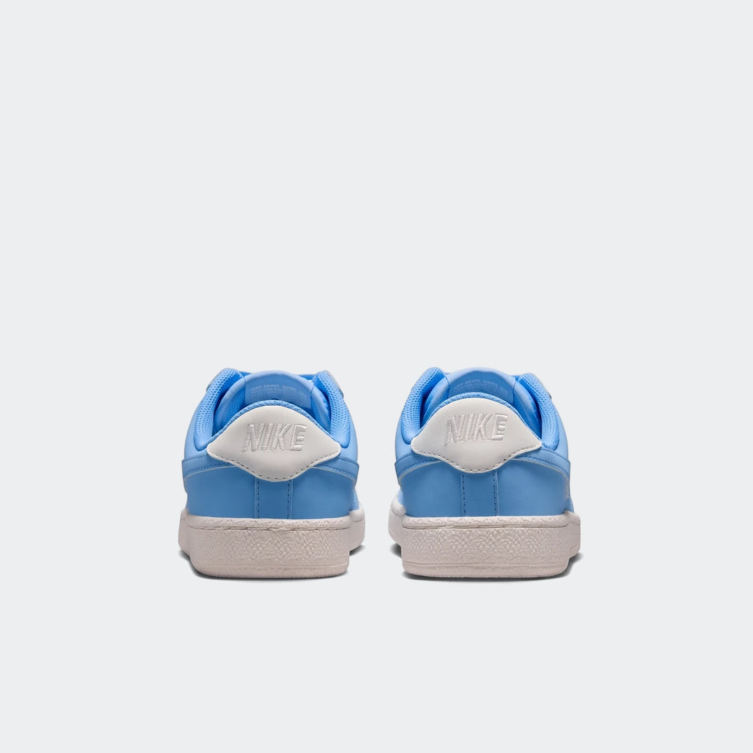 Pair of Nike Tennis Classic Big Kids' shoes in light blue and white, seen from the back view, showcasing the heel logos and