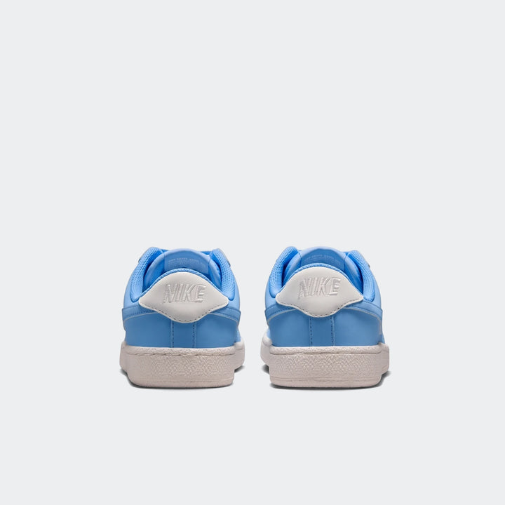 Pair of Nike Tennis Classic Big Kids' shoes in light blue and white, seen from the back view, showcasing the heel logos and